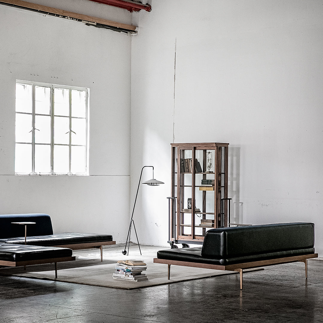 "Modern minimalist living room with black leather sofas, wood accents, and neutral-toned walls and floor."