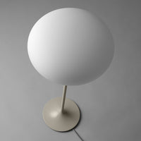 White globe lamp with a sleek beige base on a grey background, minimalistic and modern design.