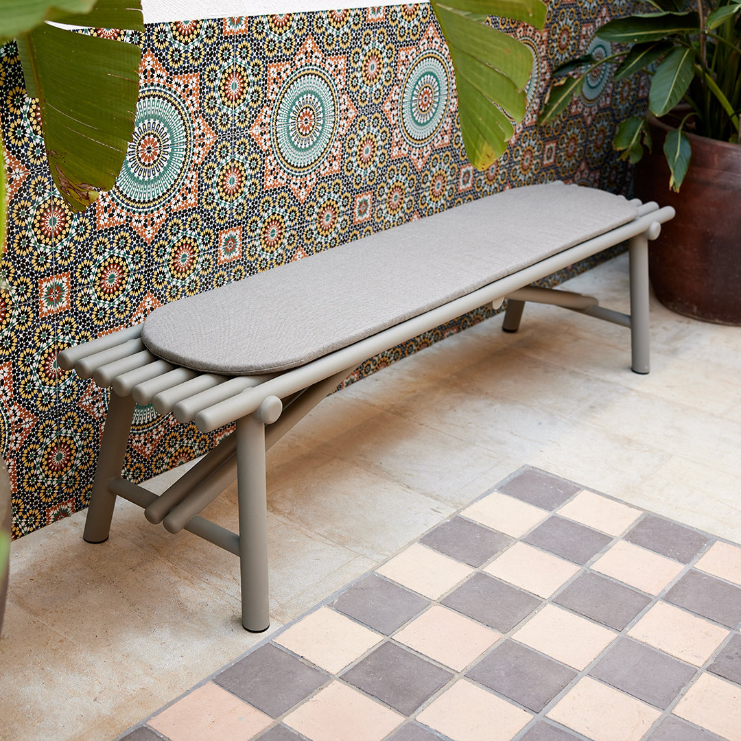 Gray outdoor bench against a vibrant, patterned backdrop with colorful circular motifs and tiled flooring.