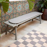 Gray outdoor bench against a vibrant, patterned backdrop with colorful circular motifs and tiled flooring.