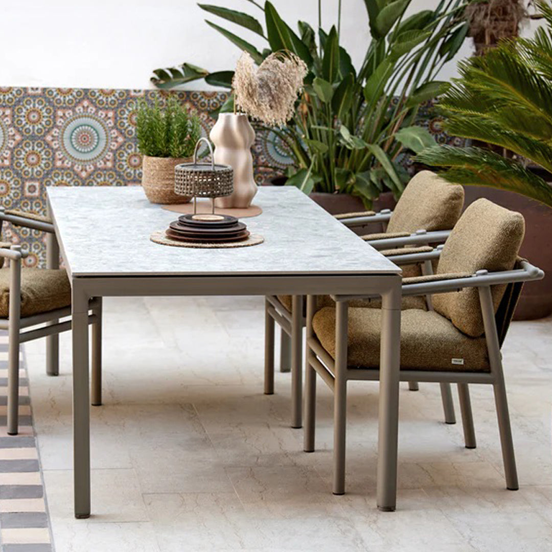 "Stylish outdoor dining table with a marble tabletop and gray aluminum frame, complemented by beige cushioned chairs."