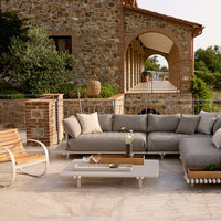 Gray outdoor sectional sofa with soft, neutral cushions, paired with a sleek white coffee table and natural wood accents.