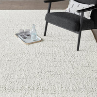 Soft, textured white rug on a light surface, complemented by a dark chair and neutral accessories.