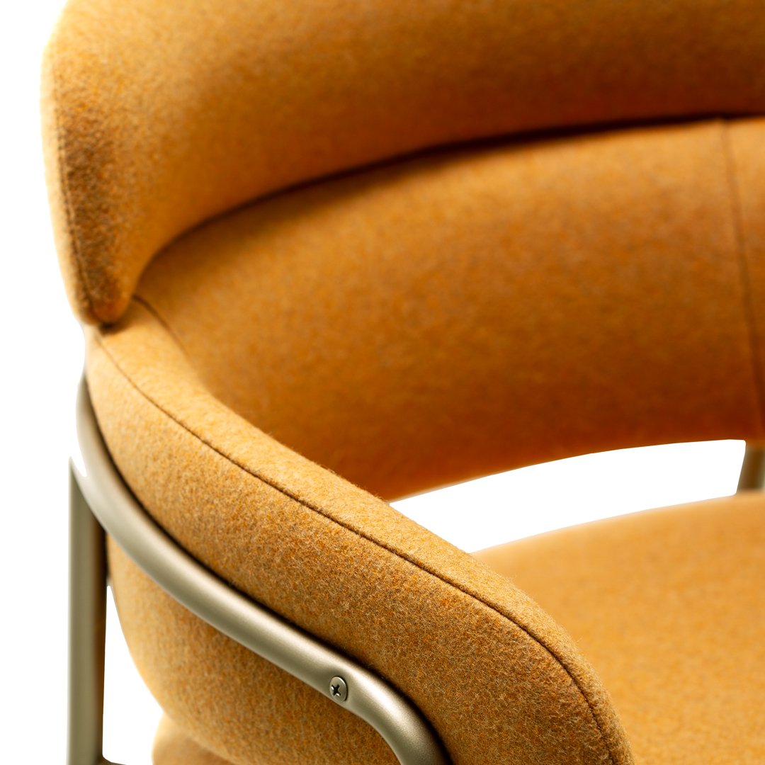 Close-up of a curved chair featuring a warm, textured orange fabric and sleek metal frame.