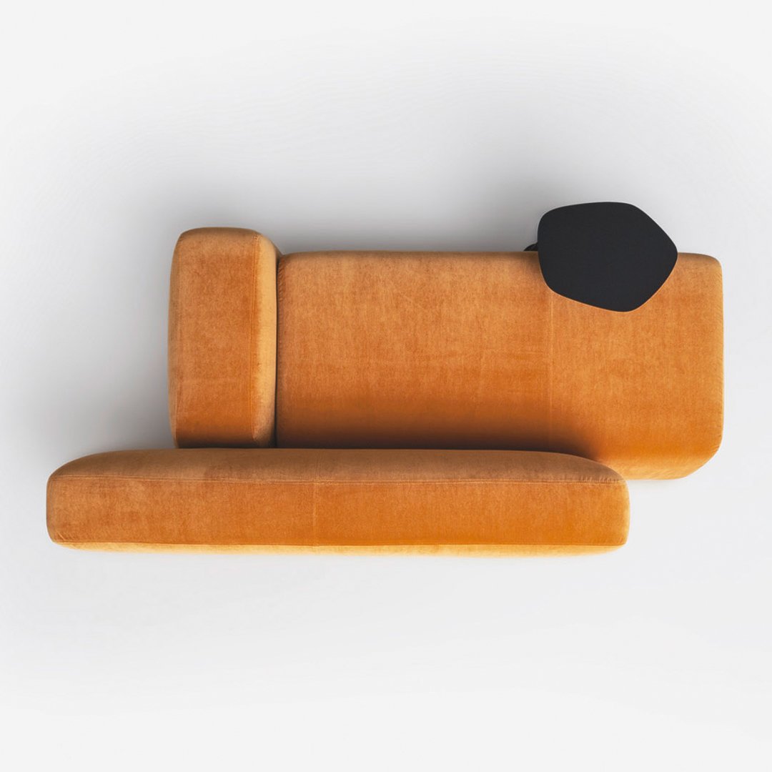 Velvet sofa in vibrant orange with a sleek black accent pillow, featuring a modern minimalist design.
