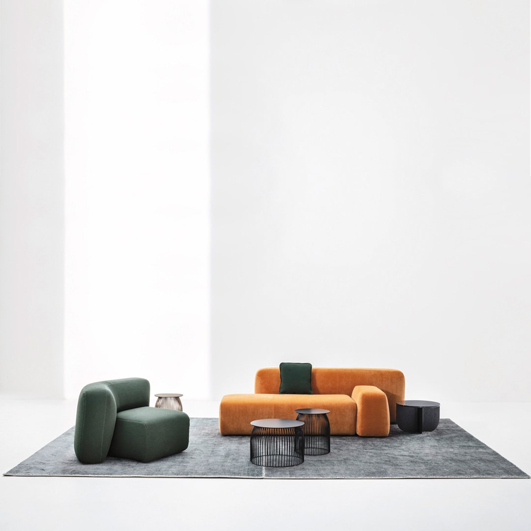 Modern sofa set featuring green, orange, and black colors on a textured gray rug. Stylish and contemporary design.