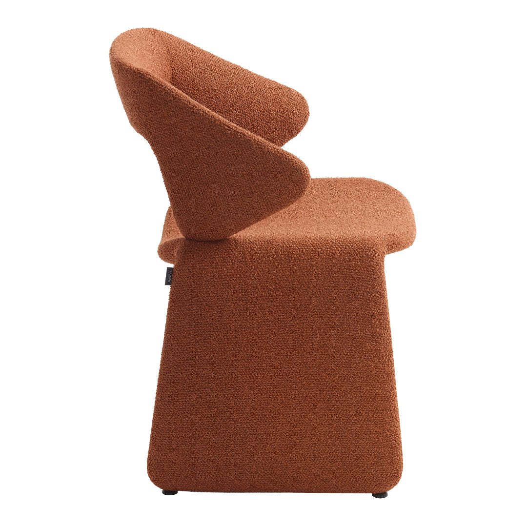 "Modern terracotta upholstered chair with a sleek, sculptural design and textured fabric."