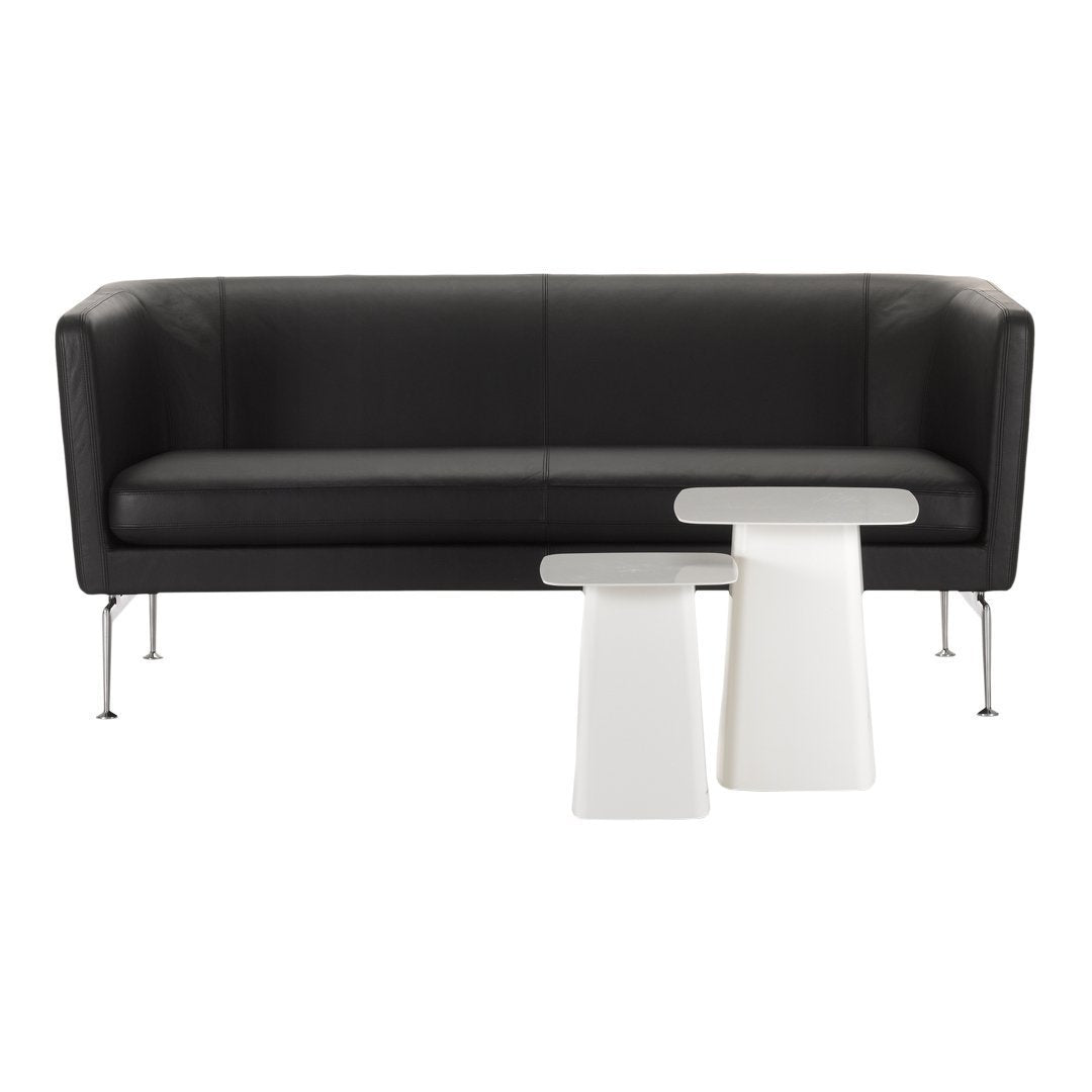 Black leather sofa with sleek lines, paired with white modern accent tables, creating a stylish contrast.