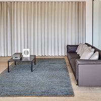 Textured blue area rug with a subtle pattern, complementing a neutral-toned sofa and light curtains.