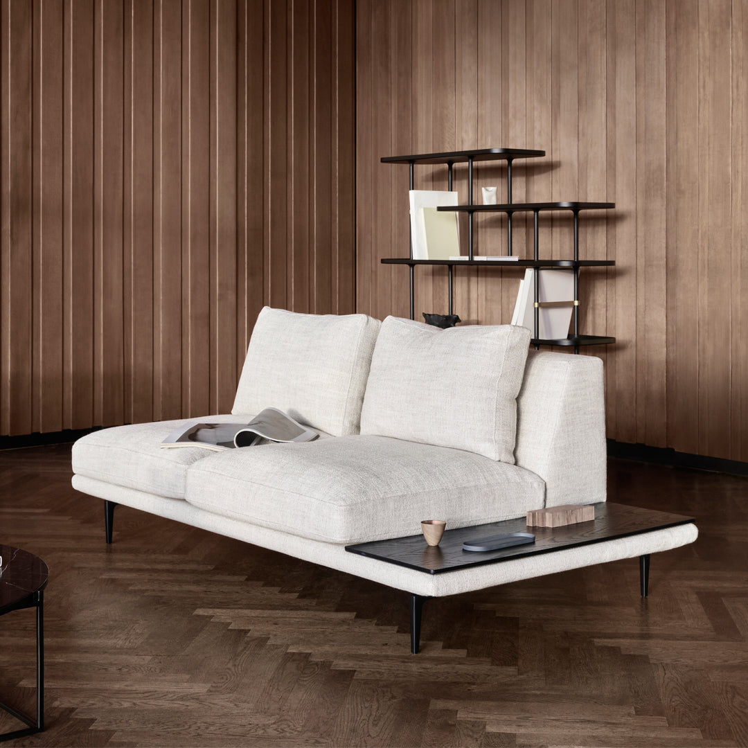 Modern white textured sofa with sleek black metal legs and a contrasting wooden backdrop.