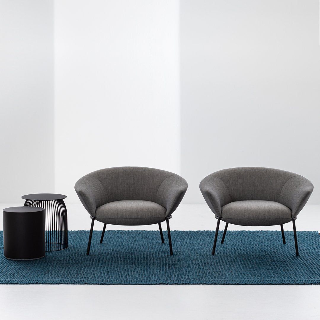 Gray upholstered chairs on a teal textured rug, paired with a sleek black side table. Modern and stylish design.
