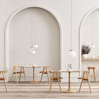 Modern dining room with white walls, wooden tables, and beige and rust-colored chairs, featuring minimalist decor.