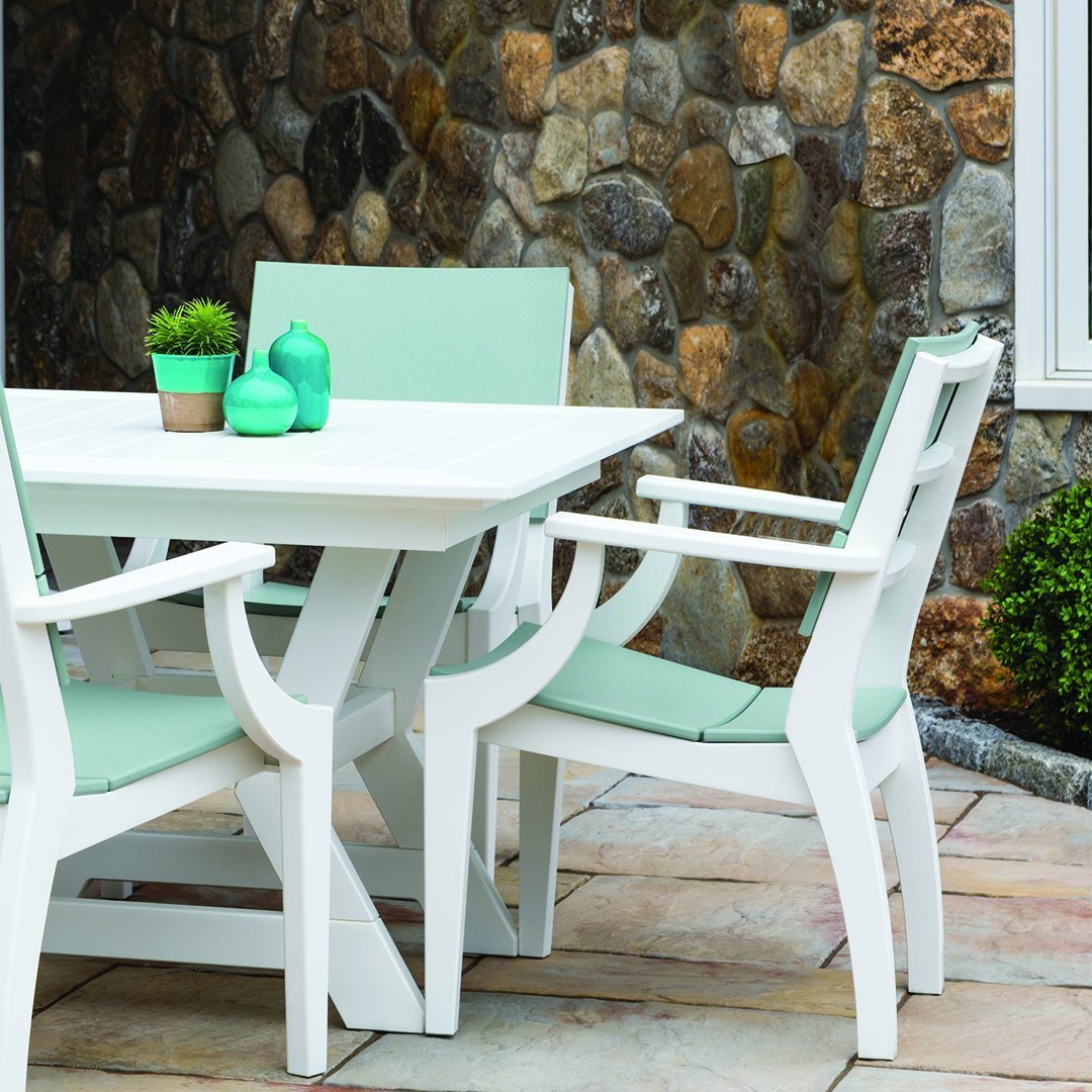 White outdoor dining set with mint green cushions, set against a textured stone wall. Modern and refreshing design.