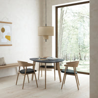 Modern round black table with light wood chairs, soft beige pendant light, and neutral wall tones.