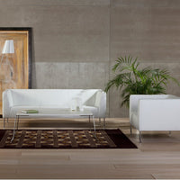 White modern sofa with geometric brown rug, accented by a sleek glass table and lush green plant.