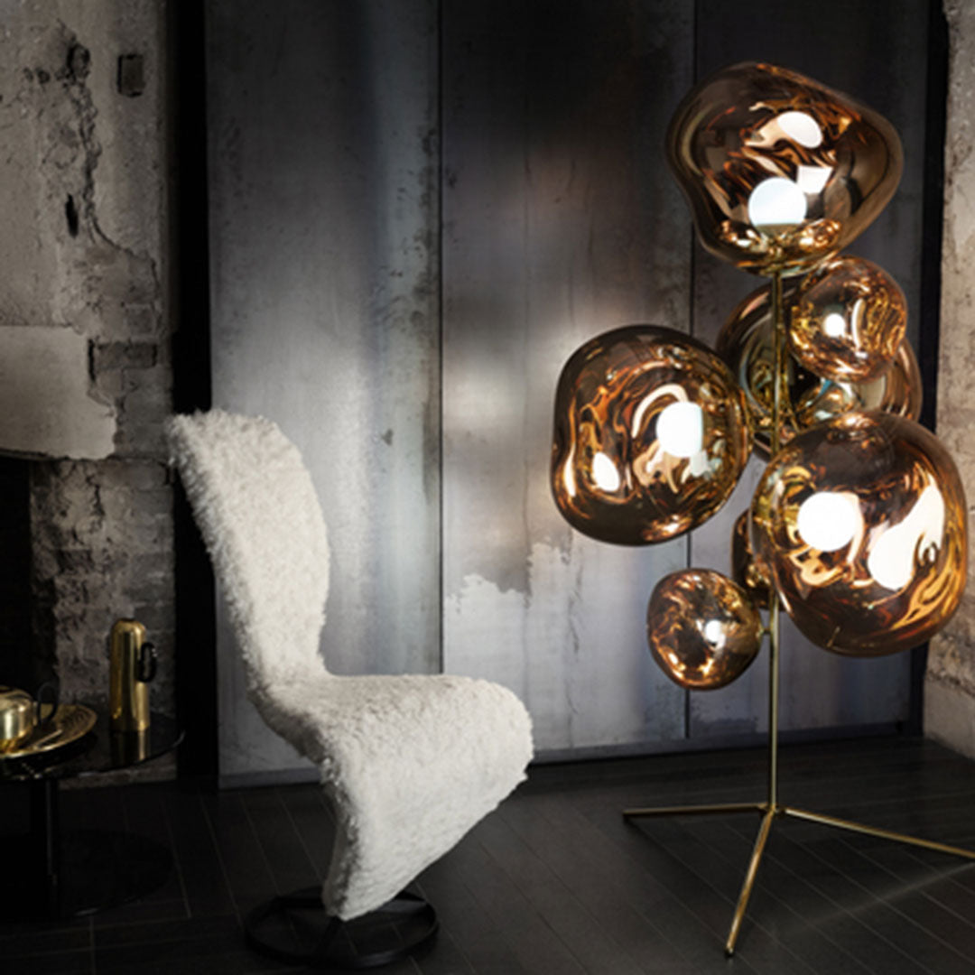Contemporary floor lamp with warm gold and clear glass bubbles, complemented by a cozy white textured chair.