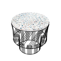 Round coffee table with a speckled white top featuring blue and orange accents, supported by a sleek black wire frame.
