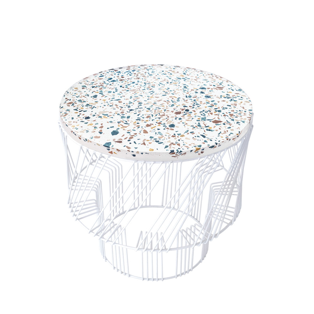 Round white wire table with a speckled top featuring blue, brown, and beige tones. Stylish, modern design.