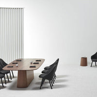 Modern conference room featuring a warm wooden table, sleek black chairs, and a soft gray carpet. Elegant minimalist design.