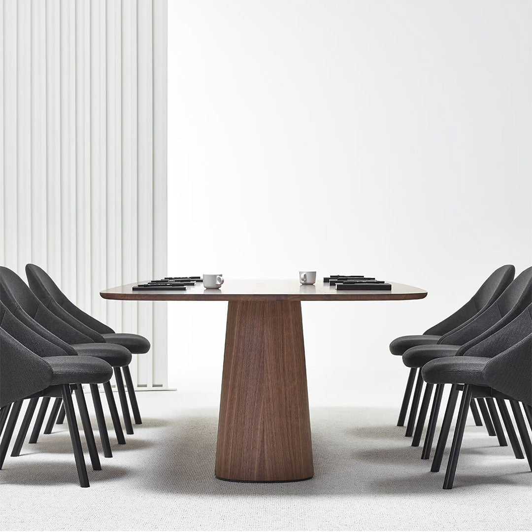 Modern grey chairs and a walnut wood table on a light beige carpet, set against a minimalistic white backdrop.