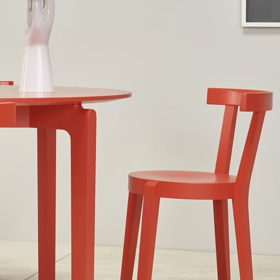 Red round table and matching chair with a smooth finish, set against a neutral background.