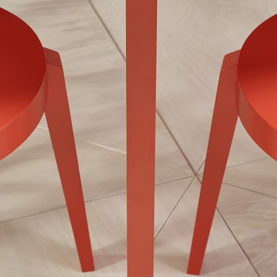 Red modern chair and table set with smooth, glossy finish, featuring a minimalist design on a light tile background.