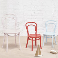 Set of three colorful chairs: pale pink, vibrant red, and soft blue against a light background.