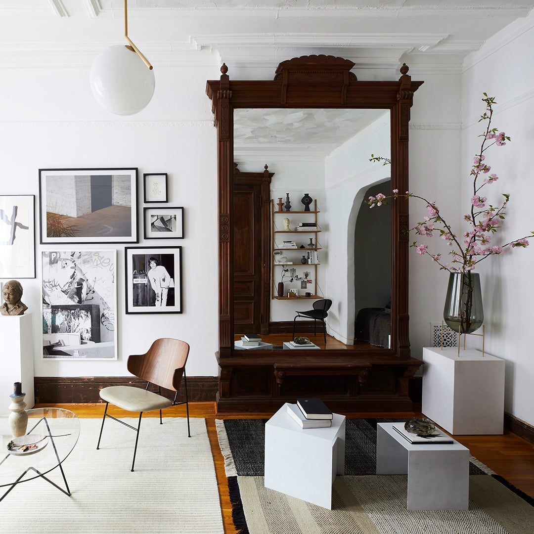 Elegant wooden mirror in rich brown, surrounded by monochrome art and sleek gray and white furniture accents.