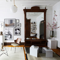 Elegant wooden mirror in rich brown, surrounded by monochrome art and sleek gray and white furniture accents.