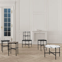 Black metal furniture with a white marble top, featuring sleek lines and minimalist design against a light wood floor.