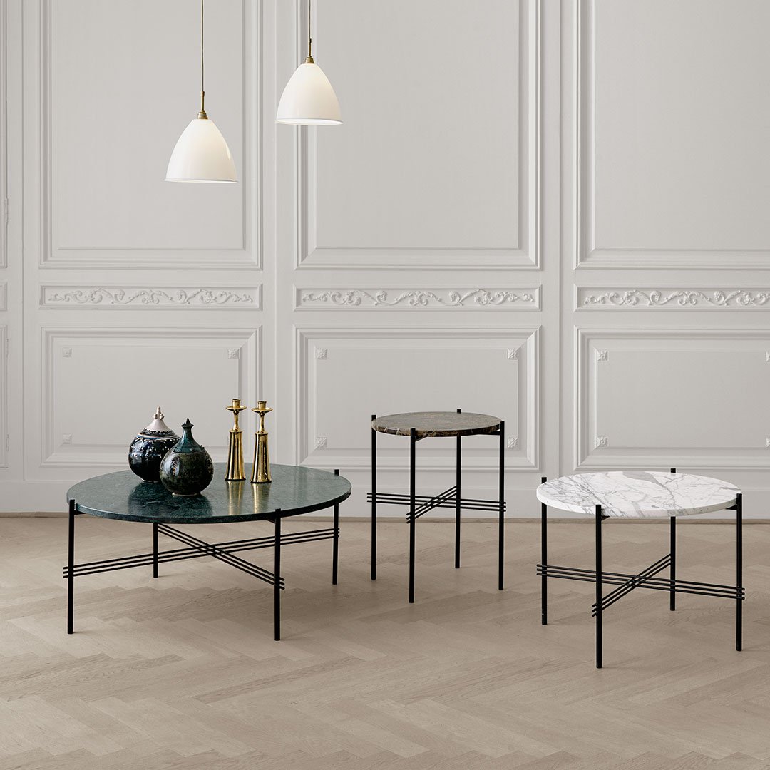 "Round green glass and white marble coffee tables with sleek black metal frames, set against a neutral wall."