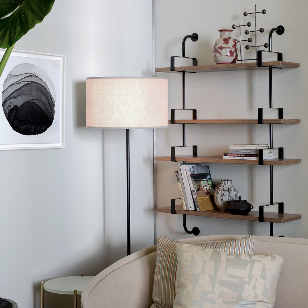 "Modern shelf with natural wood, black metal accents, and a light cream lamp; patterned pillows in soft pastel hues."