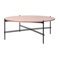 Round pink tabletop with sleek black metal legs and crossbar design, perfect for modern decor.