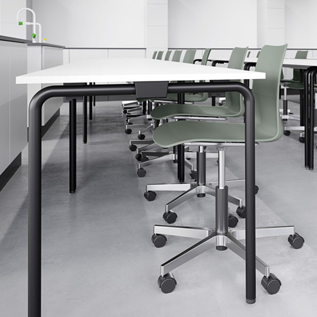 Modern workstation featuring a white tabletop, black metal legs, and green ergonomic chairs against a minimalist backdrop.