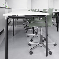 Modern workstation featuring a white tabletop, black metal legs, and green ergonomic chairs against a minimalist backdrop.