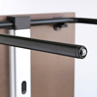 Black metal pull-up bar with a sleek finish, set against a neutral brown background. Perfect for home workouts.