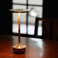 Modern table lamp in metallic gold with a textured red accent and warm glow. Ideal for stylish home decor.
