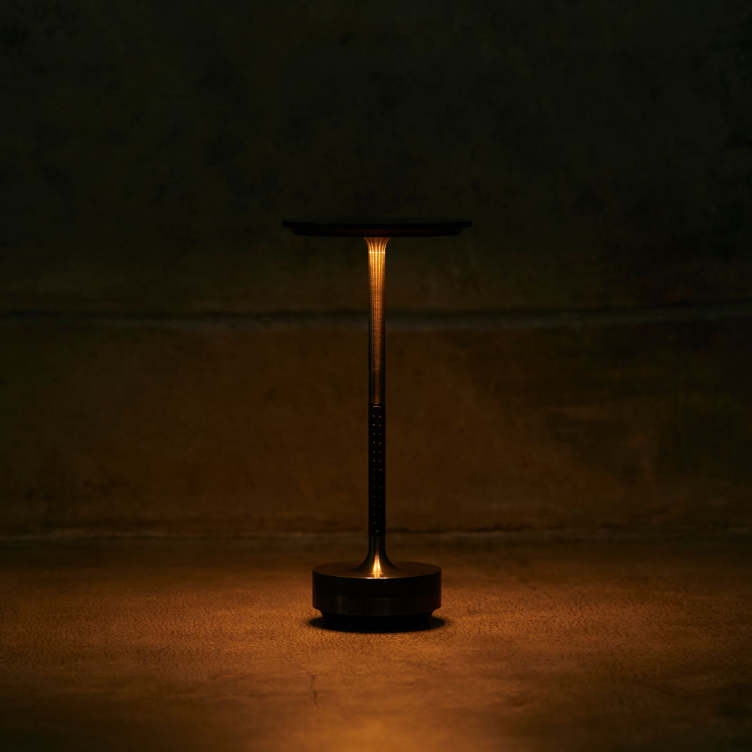 Sleek black lamp with a warm amber glow, set against a dark, textured backdrop. Modern and minimalist design.