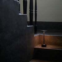 Black staircase with dark gray steps, accented by warm light from a sleek black lamp illuminating the scene.