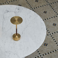 Brass lamp on a white marble table, with intricate patterned tiled flooring in muted tones and blue accents.