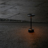 Sleek black lamp with warm orange glow on textured dark surface, creating a modern contrast in ambient lighting.