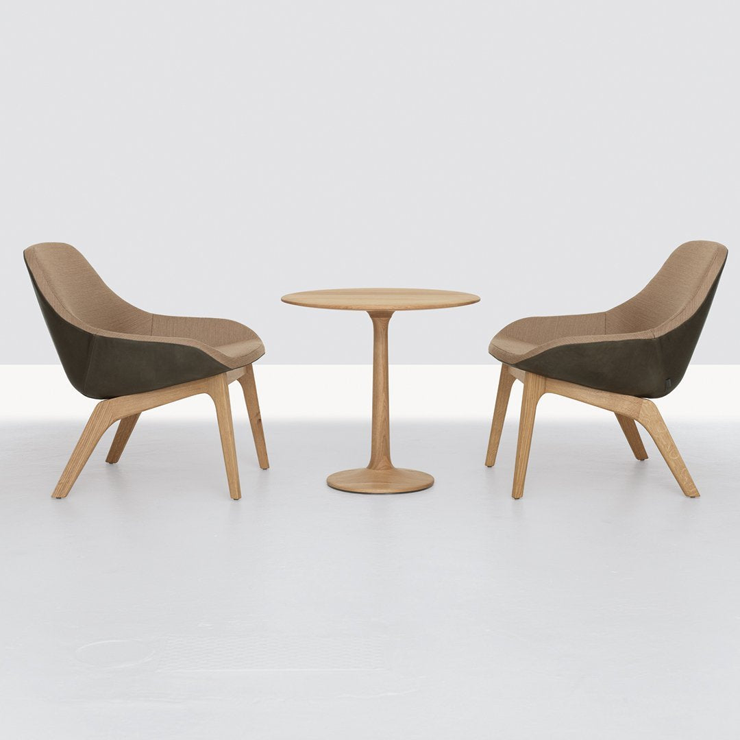 Round wooden table in light oak finish with a smooth, minimalist design and a single pedestal base.