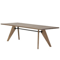 Modern wooden table with a warm oak finish and unique angled legs, featuring a sleek black metal support bar.