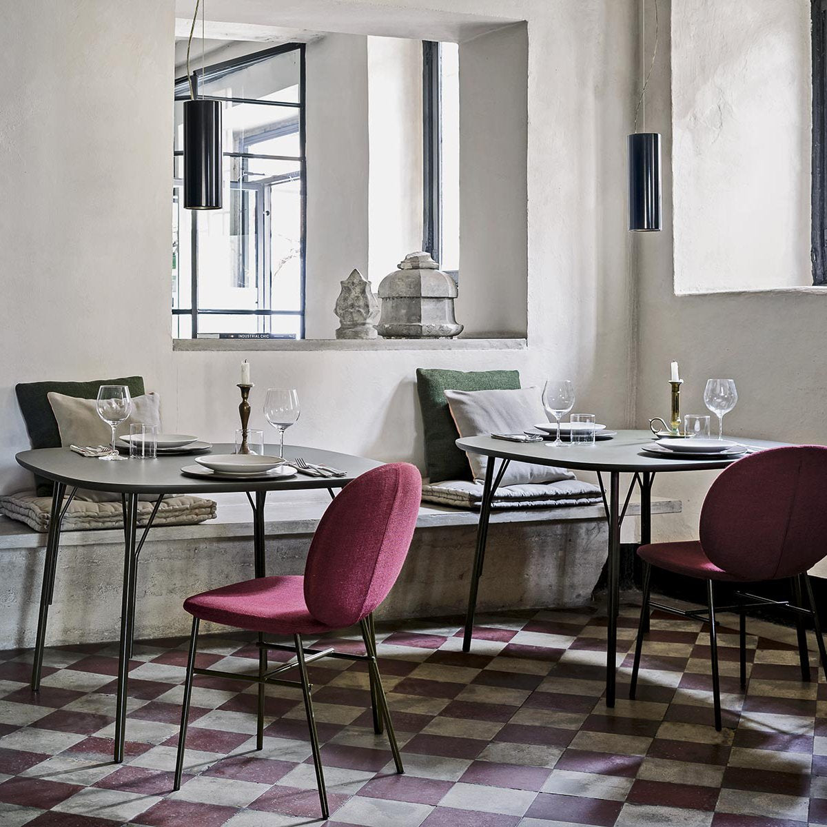 Elegant dining space with a checkerboard patterned floor in red, white, and gray, complemented by muted green and pink chairs.
