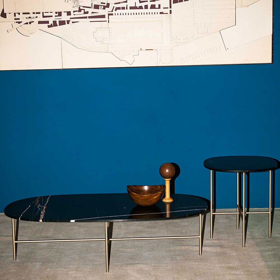 Black and patterned coffee table set against a bold blue wall, featuring elegant metallic legs.