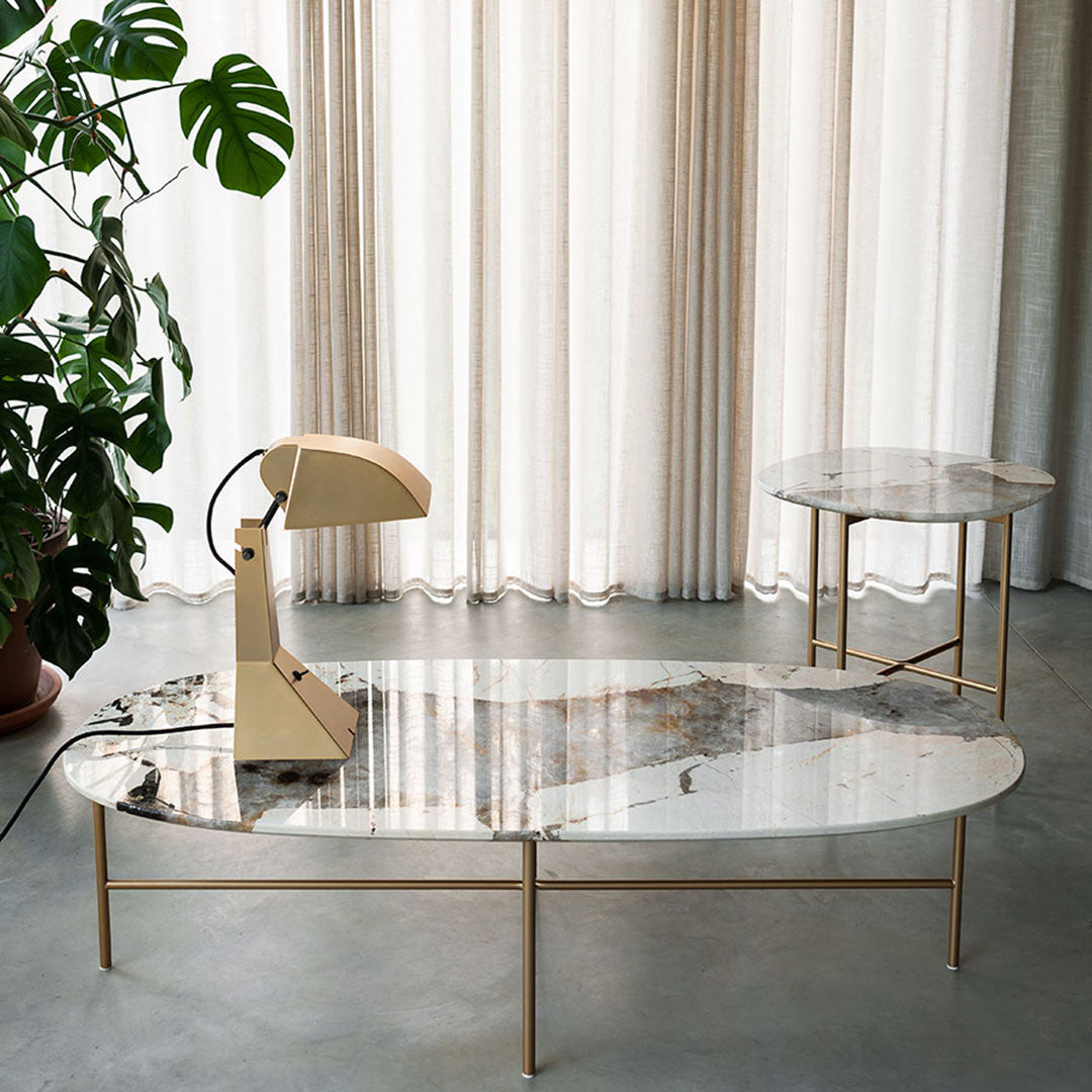 Elegant oval coffee table with marble top and gold legs, featuring soft beige, grey, and white patterns. Modern decor style.