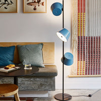 Blue tripod floor lamp with three shades, featuring a modern design against a neutral-toned backdrop.