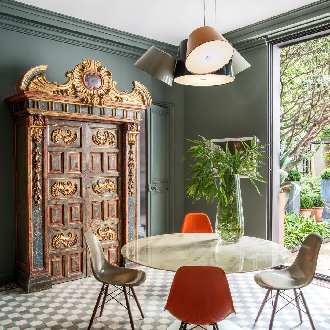 "Decorative antique wardrobe with intricate patterns, green walls, and a geometric tile floor in soft colors."