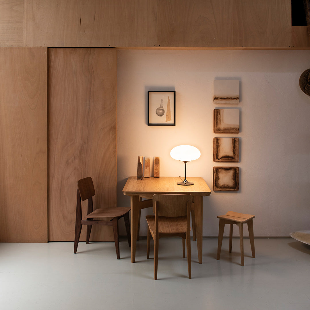 "Minimalist wooden dining set with warm tones and natural textures, featuring a soft glow from a round table lamp."