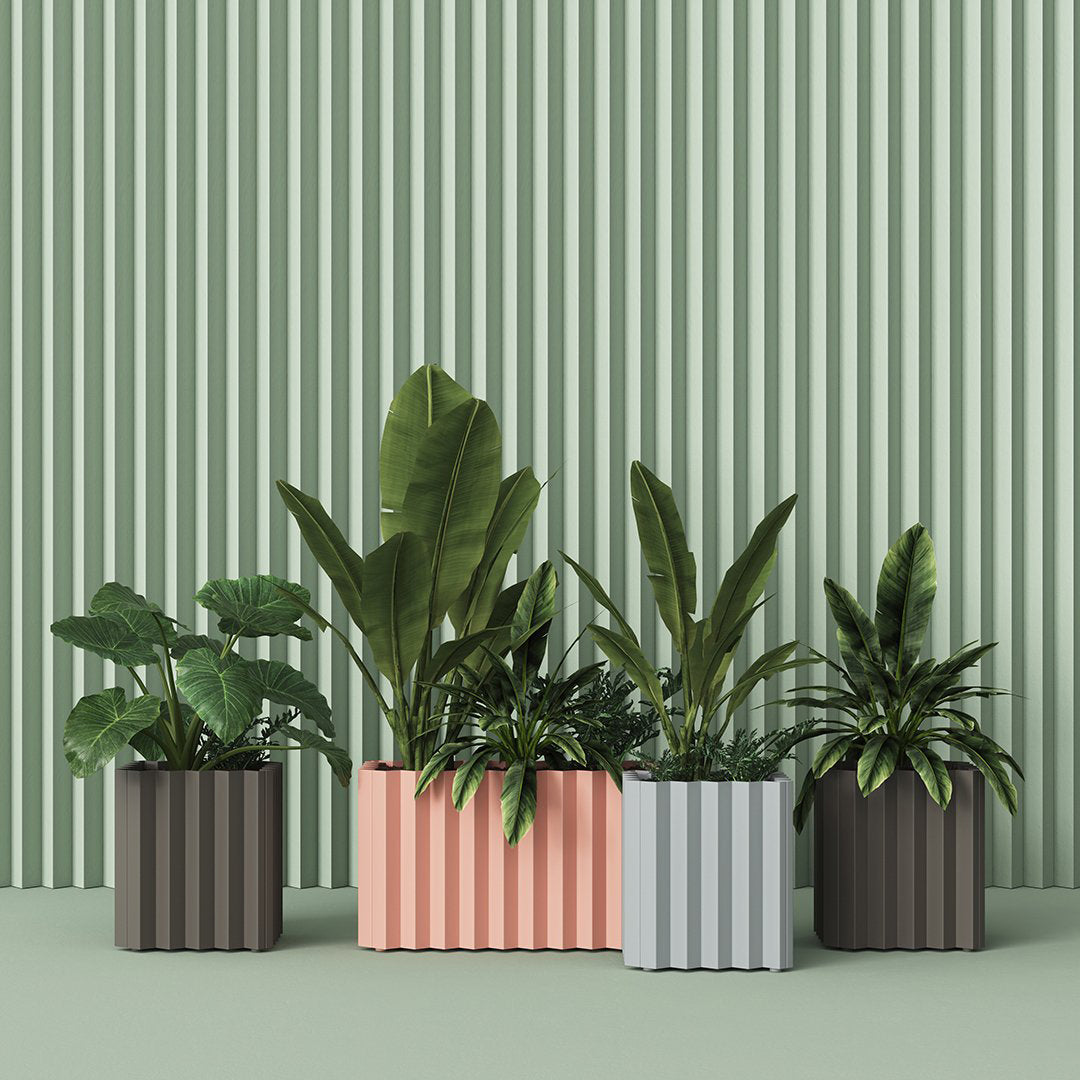 "Modern planters in pastel peach, grey, and dark tones against a textured green backdrop, showcasing unique vertical stripes."
